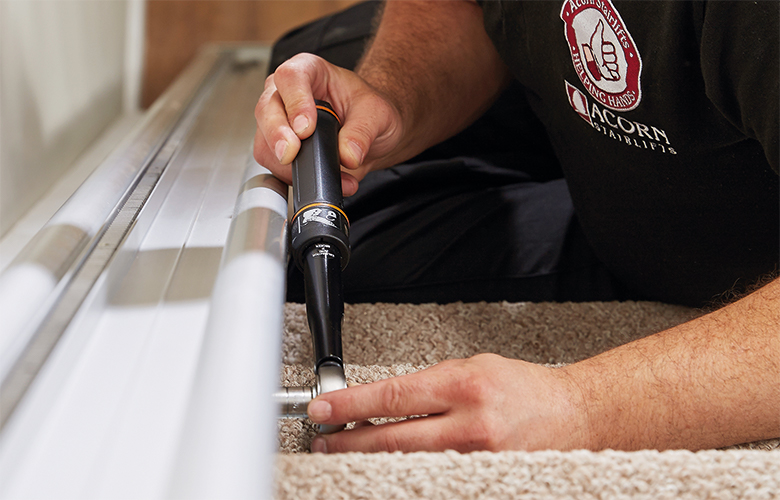 Stairlift expert using wrench to tighten rail to the stairs